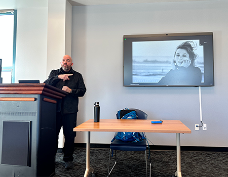 Otávio Bueno giving a lecture about film with an image from a French film behind him on a screen.