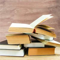 A stack of books with one open on top.