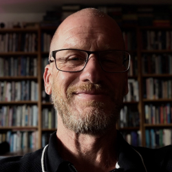 Jamie Lindsay smiling in front of books.
