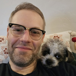 Matthew Noller, smiling with a tiny dog.