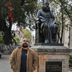 Photo of Lenin Silva in front of a statue of Cervantes.