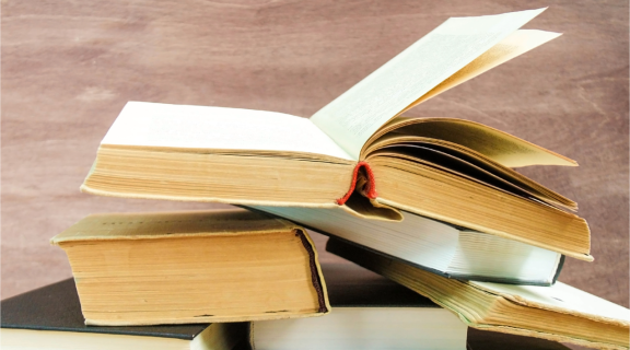 A stack of books with one open on top.